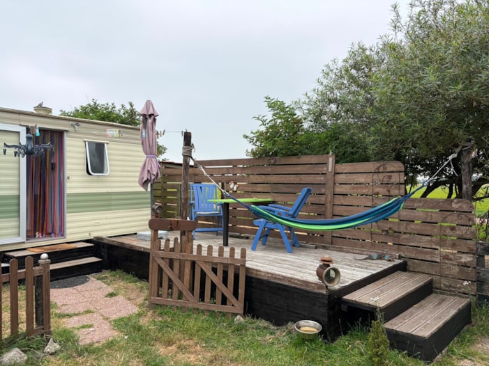 caravan buiten met hangmat en tafeltje geschilderd